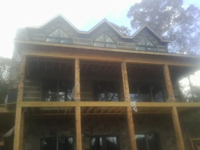 Dormers and porch framing on a large log home under construction — Roof Coating work by our crew in East Dubuque