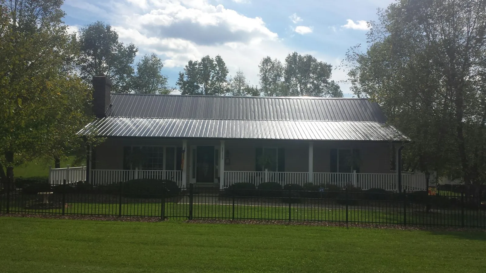 Gray metal roof on a brick ranch with a full width front porch — Gutter Guard Installation work by our crew in East Dubuque