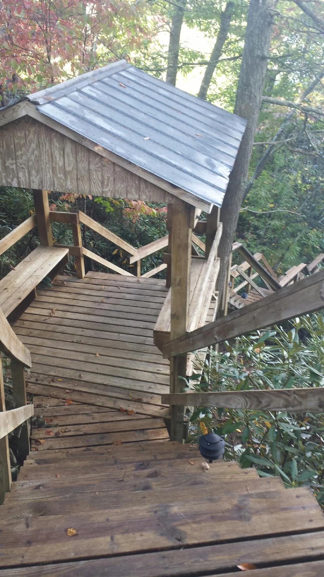 Metal roofed shelter over wooden steps on a wooded walkway — Skylight Repair & Installation work by our crew in East Dubuque