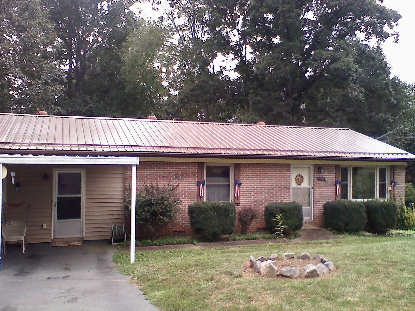 Bronze metal roof and carport on a brick ranch home — Roof Repair work by our crew in East Dubuque