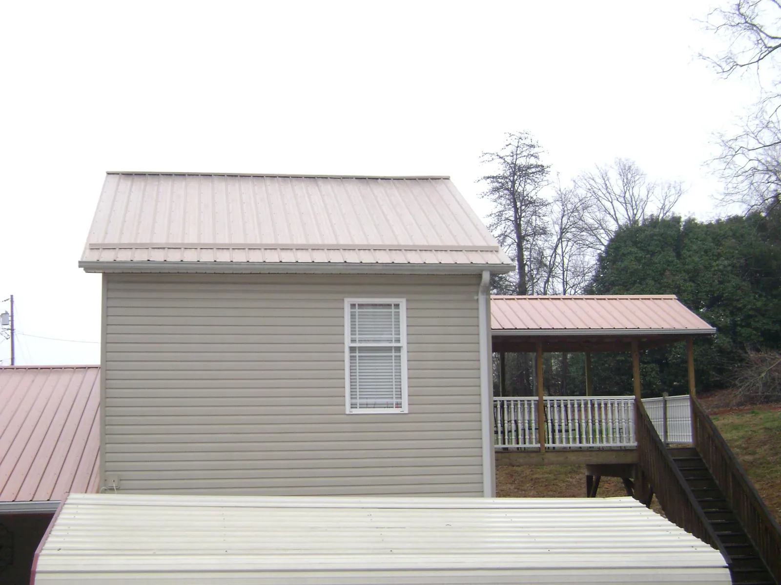 Tan metal roofs on a two story addition and attached porch, from a Roof Replacement job in East Dubuque