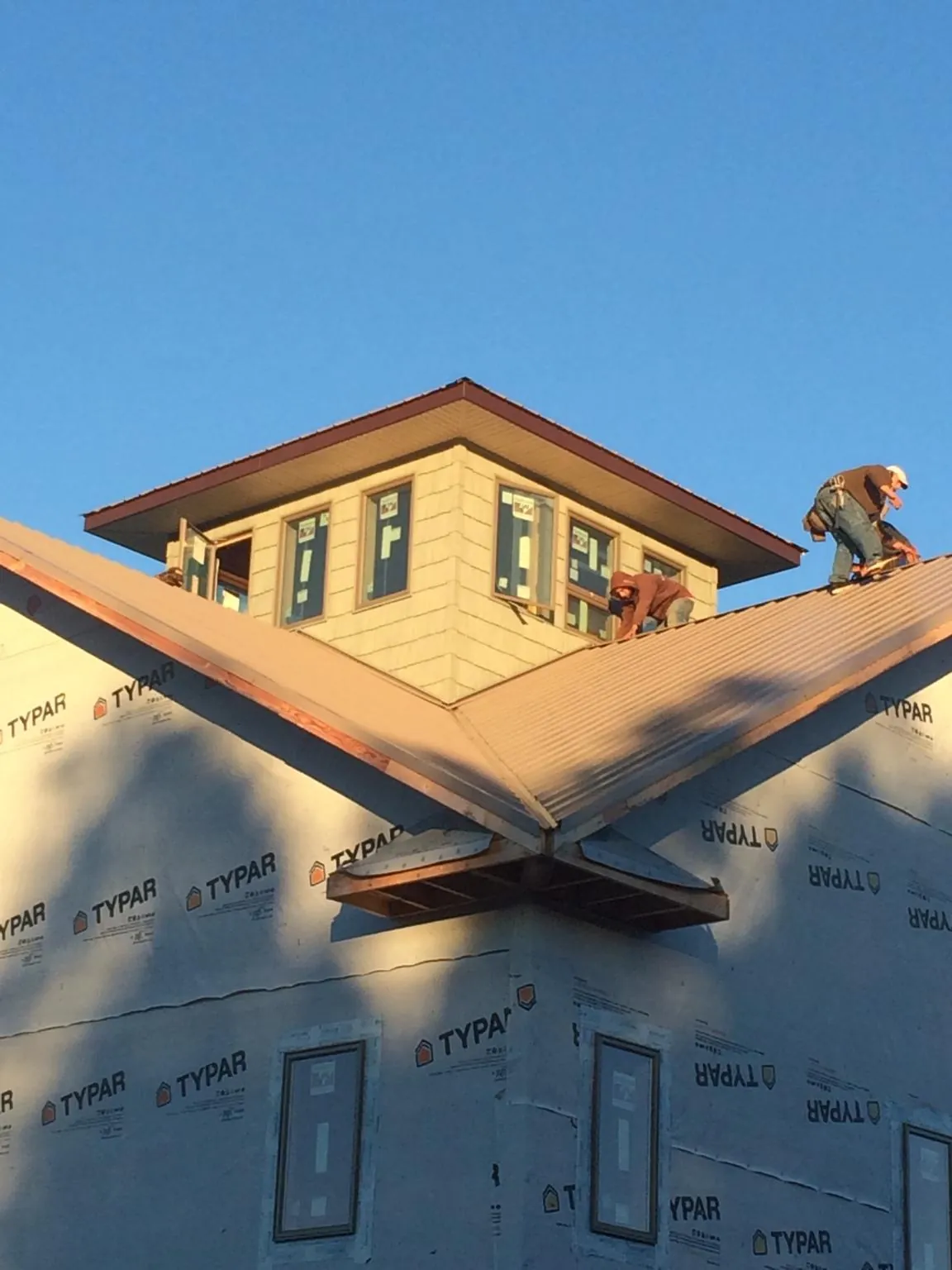 Roofers working around a rooftop cupola on a new metal roof at sunset — Roof Waterproofing in East Dubuque by Roofing Brothers